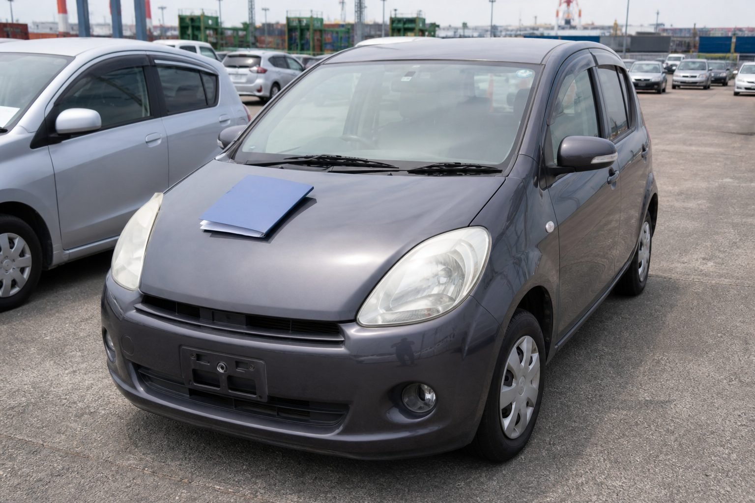 Used car in a Japanese export yard with a shipping document folder